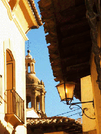 Farol de hierro forjado y campanario al fondo